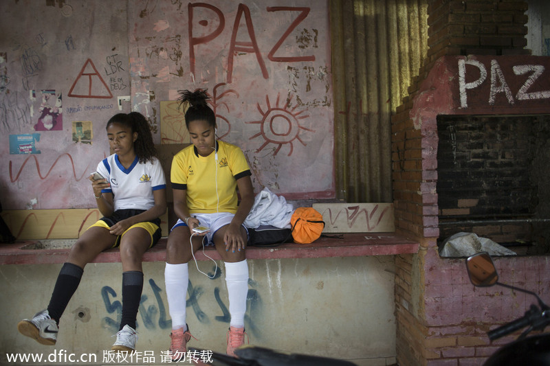 Deux adolescentes s’amusent avec leurs téléphones portables en attendant de disputer un match de football dans le bidonville de Borel à Rio de Janeiro, au Brésil, le 10 mai 2014. [Photo/IC]