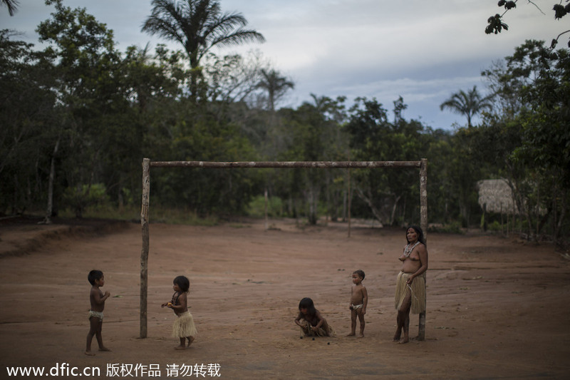 Des enfants et une femme venant de diverses tribus présents sur un terrain de football de la communauté autochtone de Tatuyo, près de Manaus, au Brésil, le 19 mai 2014. Manaus est l’une des villes hôtes de la Coupe du Monde 2014 au Brésil. [Photo/IC]