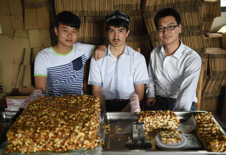 Adili (au milieu), Jiang Jinya (à droite) et Jiang Chunyang (à gauche) prennent une photo de groupe dans leur atelier à Changsha, dans la province du Hunan, le 22 mai 2014. [Photo/Xinhua]