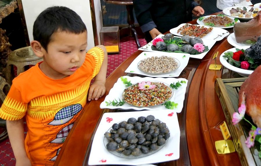 Un jeune visiteur admire des plats faits en pierre lors d’une exposition dans la préfecture de Hami, lundi dans la Région autonome ouïgoure du Xinjiang. [Photo / Xinhua]