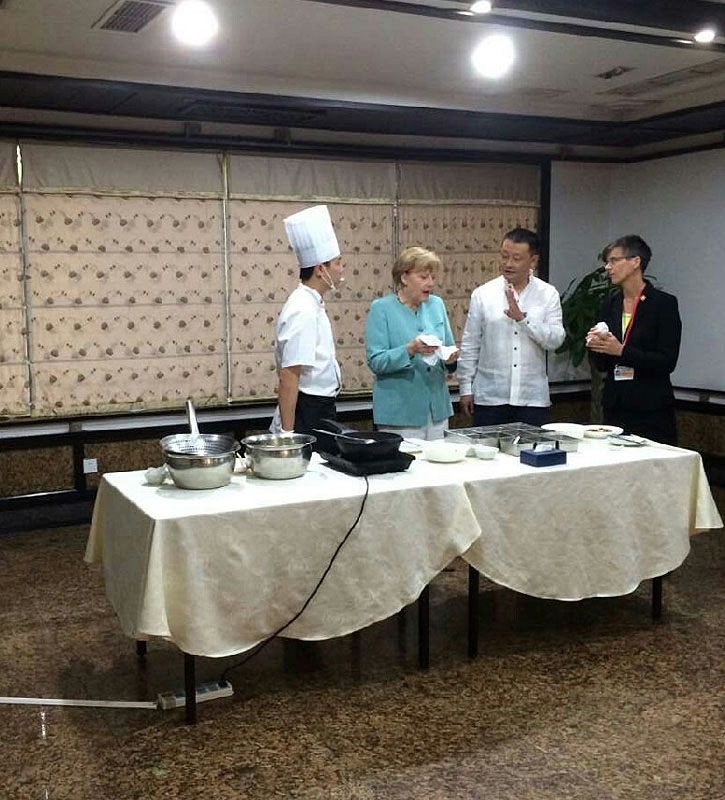 La chancelière allemande Angela Merkel savoure un poulet kungpao, un plat épicé du Sichuan à base de poulet, d'arachides, de légumes et de piments, lors de sa visite à Chengdu, la capitale de la province du Sichuan (sud de la Chine), le 6 juillet 2014. Merkel a débuté son 7ème voyage en Chine dimanche dans la ville du sud-ouest, un endroit que les entreprises allemandes considèrent comme un tremplin pour les parties relativement sous-développées de l'ouest de la Chine. [photo China Daily] 