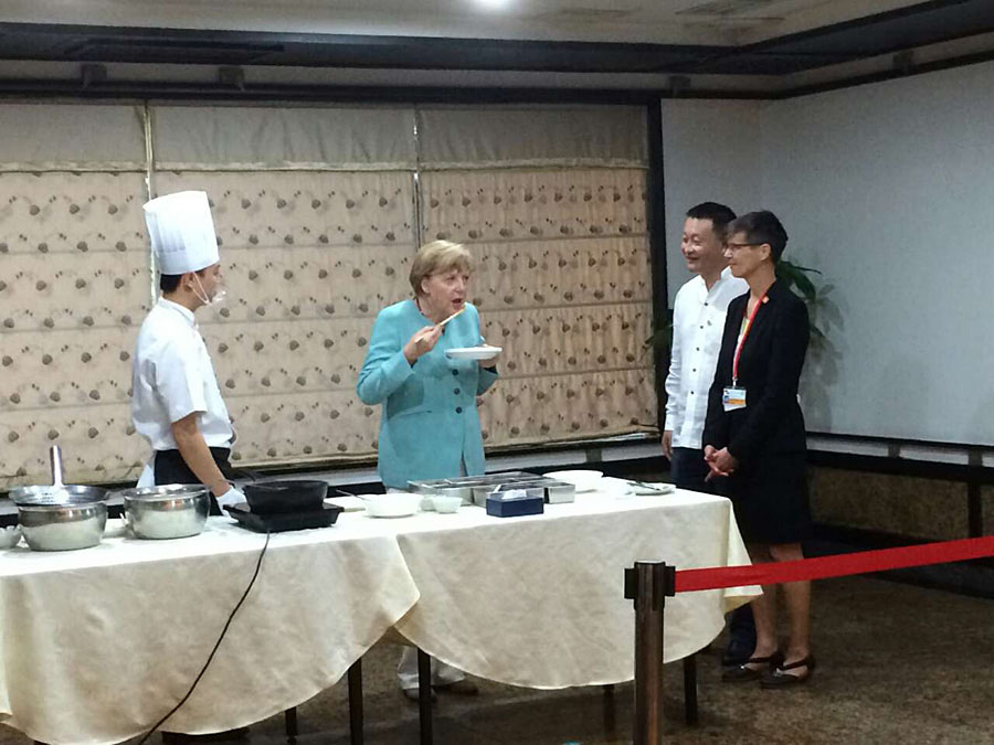 La chancelière allemande Angela Merkel discute avec à un vendeur lors de sa visite dans un marché ouvert à Chengdu, la capitale de la province du Sichuan (sud de la Chine), le 6 juillet 2014. Merkel a marqué de son empreinte le quotidien de la ville en visitant un marché ouvert et acheté un sac de fève pâte pour 5 yuans (0,8 $). [Photo: Peng Chao/chinadaily.com.cn]