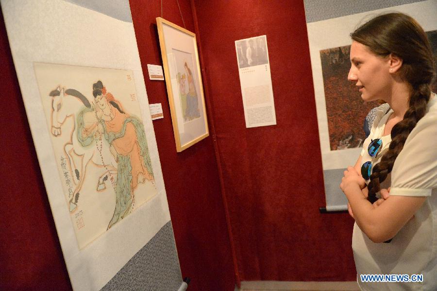 Une femme regarde une peinture chinoise traditionnelle lors d'une exposition de la calligraphie et de la peinture traditionnelle chinoises à Tirana, capitale de l'Albanie, le 25 juillet 2014.