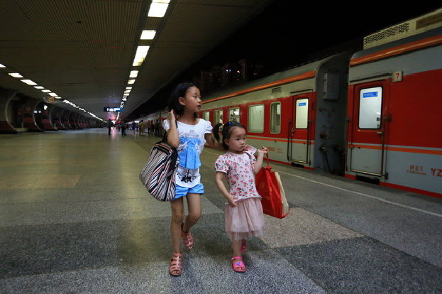 Wu Jinjuan, à gauche, emmène sa sœur cadette Siyu pour prendre un train de Guilin vers le Guangdong, le 9 juillet 2014.