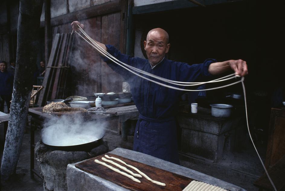 Une personne âgée prépare des nouilles dans les rues de Chengdu (1980). 