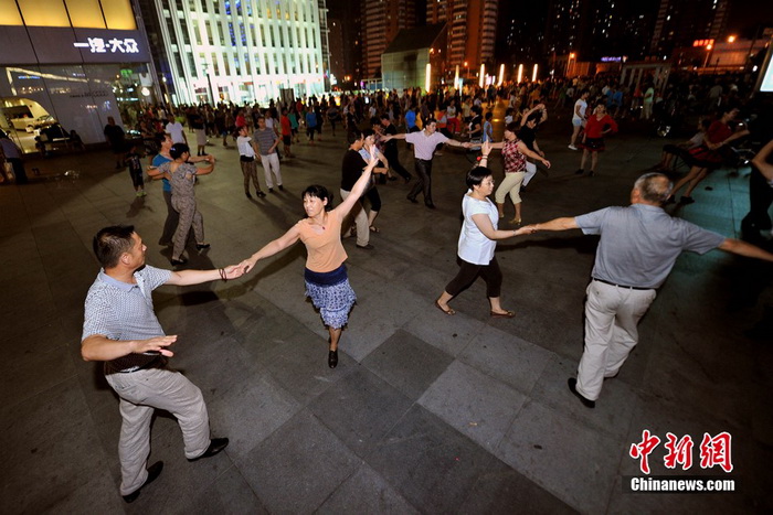La danse de square « Centre de l'univers » devant le centre commercial Joy City de Shuangjing. Ici se réunissent tous les soirs à 19h trois générations de danseurs qui arrivent petit à petit, formant toutes sortes de petits groupes séparés de danse de square, qui ont tôt fait de remplir cet endroit. Photo Jin Shuo pour Xinhua. 