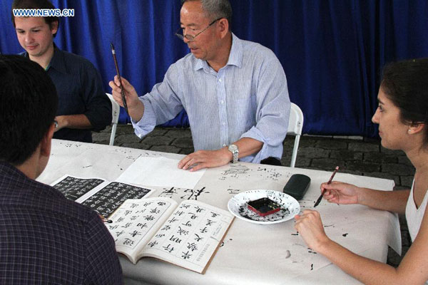 Le professeur Hang Qingxu (au centre) de l'Institut Confucius de l'Université du Costa Rica, donne un cours de calligraphie à l’occasion de la Journée des Instituts Confucius, à San José, la capitale du Costa Rica, le 26 septembre 2014. 