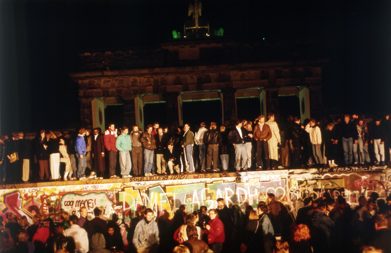 Des berlinois venus de l'Est mais aussi de l'Ouest devant la Porte de Brandebourg, se tiennent sur ou sous le mur de Berlin, qui séparait la ville depuis la fin de la Deuxième Guerre mondiale, le 10 novembre 1989.