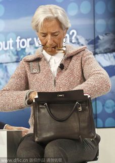 Christine Lagarde, Directrice générale du Fonds monétaire international (FMI), fouille dans son sac devant un panneau du Forum de Davos, le 23 janvier 2015. [Photo/IC]