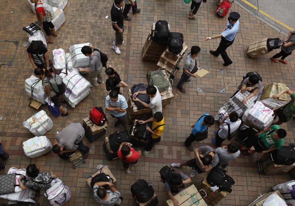 Des policiers rappellent des touristes à ne pas bloquer des passages piétons à une gare à Hong Kong. En même temps que les touristes de la partie continentale de Chine ont contribué à la croissance économique, ils ont également perturbé la vie des résidents.