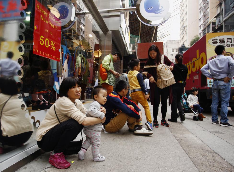 Des touristes se reposent à l'extérieur d'un magasin à Hong Kong.