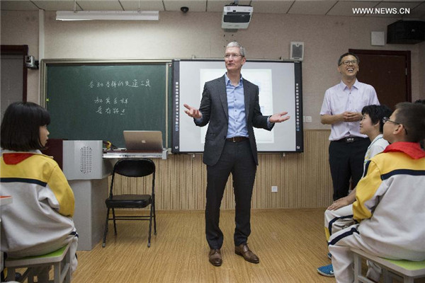 Tim Cook, au centre, échange avec des élèves lors d’une leçon à l'école primaire de l'Université de Communication de Chine, le 12 mai 2015. [Photo / Xinhua]