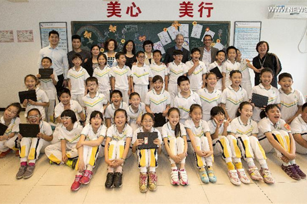 Tim Cook, au fond à droite, pose pour une photo de groupe avec les enseignants et les élèves de l'école primaire de l'Université de Communication de Chine, le 12 mai 2015. [Photo / Xinhua]