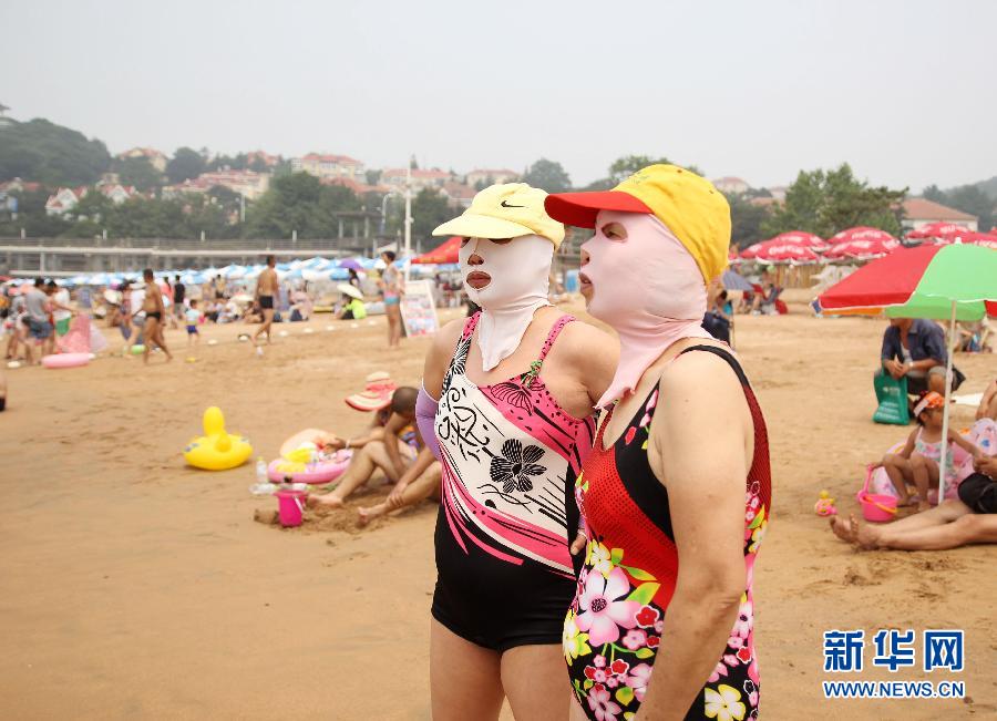 Des chinoises portent des cagoules sur une plage de Qingdao, le 13 juillet 2015.