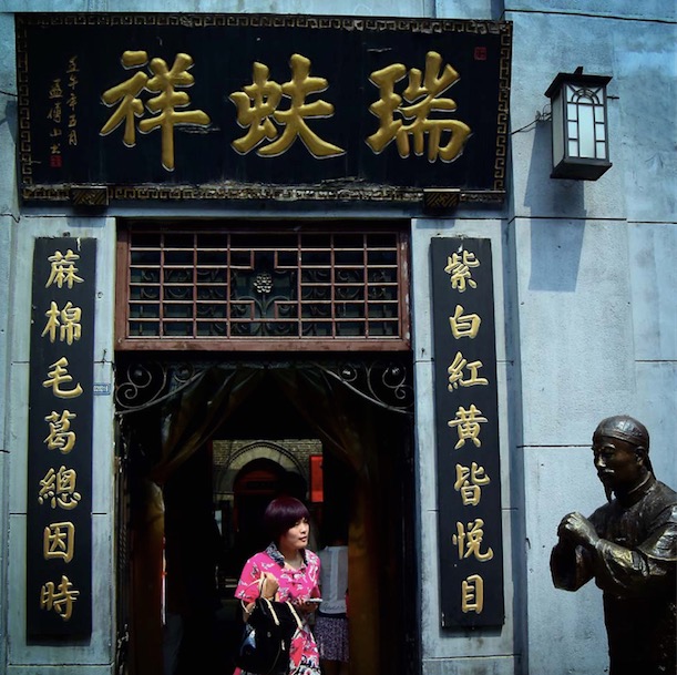 Une femme sort d'une boutique traditionnelle de vêtements de Ruifuxiang dans l'ancien village de Zhoucun de la ville de Zibo, dans la province chinoise du Shandong (est), le 10 juin 2015.