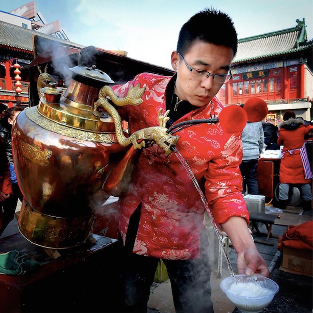 Un homme sert du thé à l'amande à des clients dans une ancienne rue de la municipalité chinoise de Tianjin (nord), le 5 mars 2015.