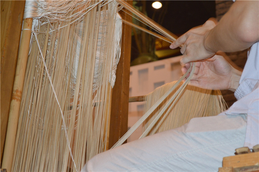 La personne qui travaille au sommet du métier à tisser est en charge de la création du motif en tirant les fils. [Photo Jiang Wanjuan / chinadaily.com.cn]