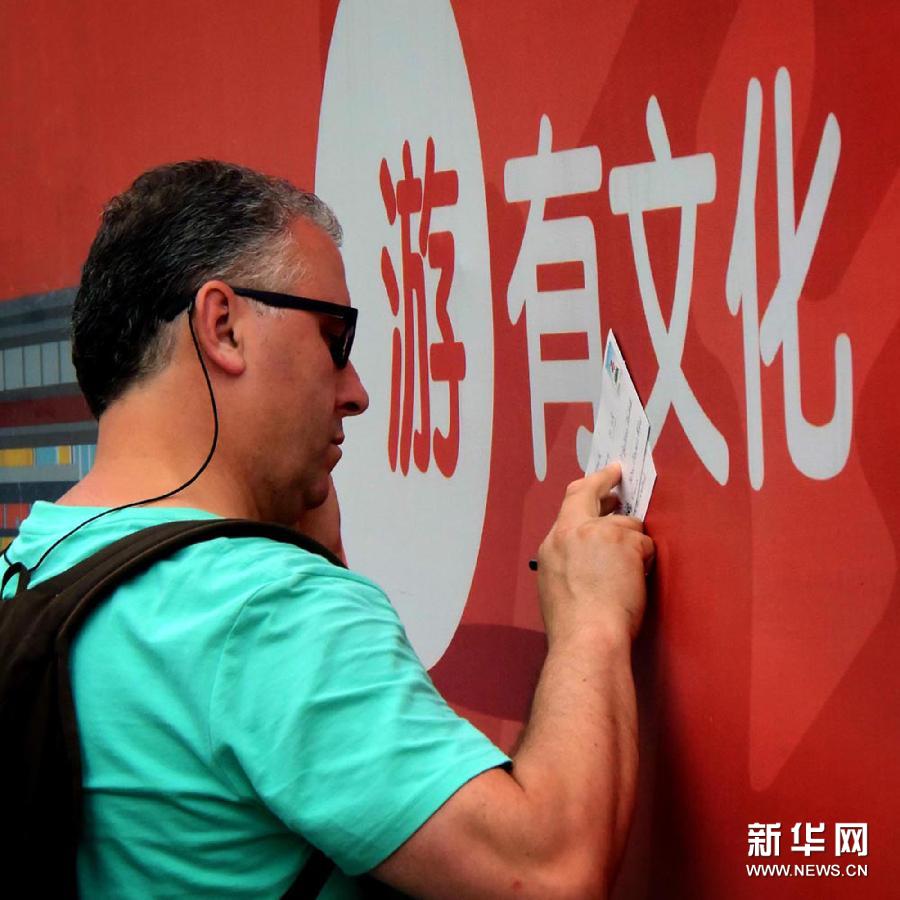 Un touriste étranger écrit une carte postale dans un hutong de Nanluoguxiang à Beijing.
