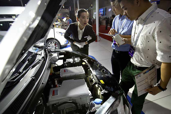 Un membre du personnel discute avec des visiteurs qui regardent le moteur d'un SUV tout électrique iEV5 du constructeur chinois JAC, exposé lors du Salon international de l'auto de Beijing International, le 25 avril 2016. [Photo / IC]