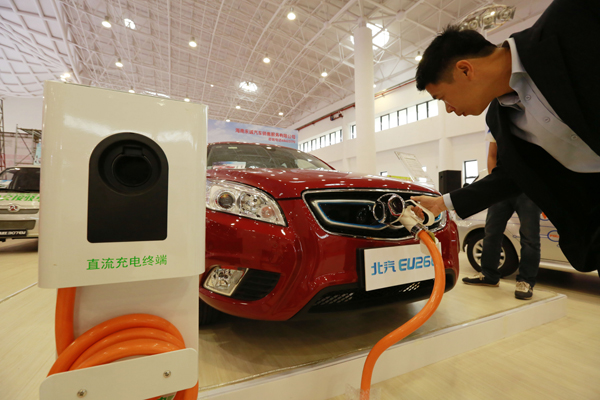 À Hainan, où le secteur des véhicules à énergie nouvelle connaît un fort engouement, un visiteur s'essaye à la recharge d'un véhicule électrique. [Crédit photo : China Daily]