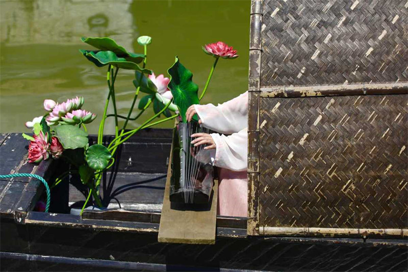 Une artiste joue du guqin, un instrument chinois traditionnel à sept cordes, sur un bateau du village de Yigao de Huzhou, dans la province du Zhejiang (est de la Chine). (Zhu Xingxin / chinadaily.com.cn)