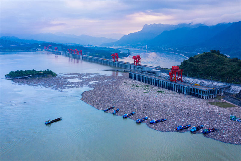 Des bateaux nettoient les objets flottants devant le barrage des Trois Gorges à Yichang, dans le Hubei