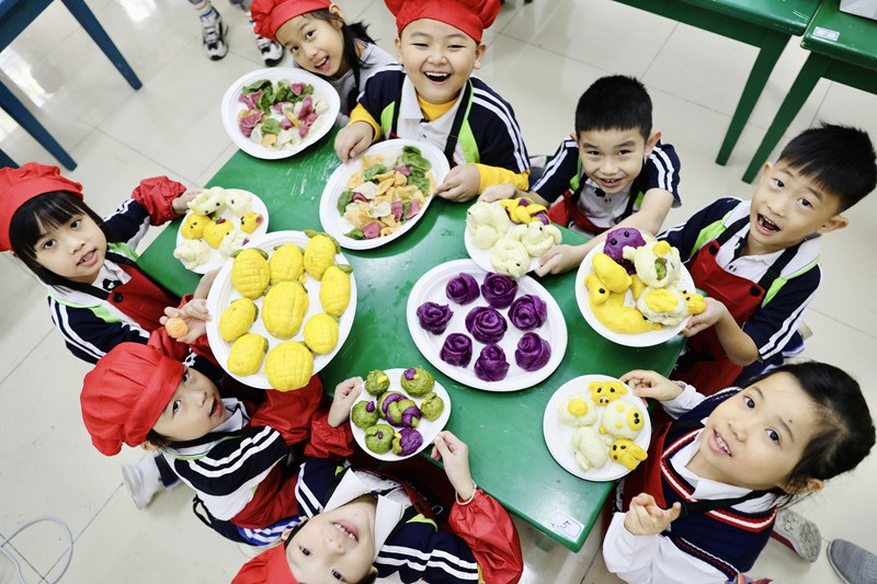 Des enfants montrent les pâtisseries auxquelles ils ont participé à la cuisine. (Fu Wuping/le Quotidien du Peuple en ligne)