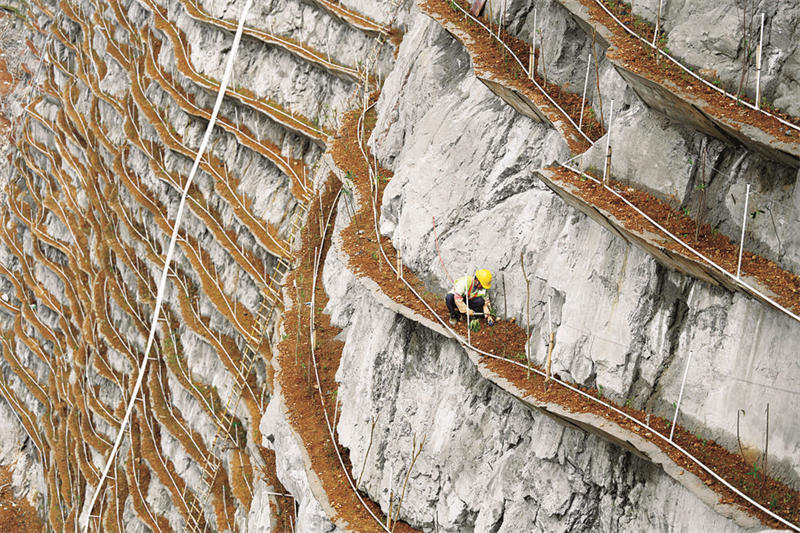 En mars 2021, les ouvriers plantent des semis sur les rigoles étroites du mont Louti dans le cadre du projet de reverdissement. (Li Hanchi/Le Quotidien du Peuple en ligne)