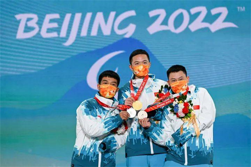 Le 7 mars, les athlètes chinois Ji Lijia (au centre), Wang Pengyao (à gauche) et Zhu Yonggang (à droite), lors de la cérémonie de remise des prix de l'épreuve para snowboard cross hommes (SB-UL) des Jeux paralympiques d'hiver de Beijing 2022. (Hu Chao / Xinhua)