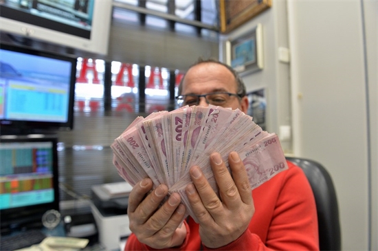 Un caissier montrant des billets de banque en livre turque dans un bureau de change à Ankara, en Turquie, le 11 avril 2023. (Xinhua/Mustafa Kaya)