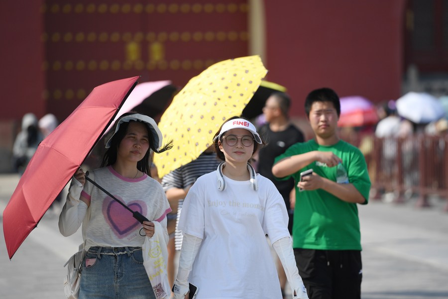 Des touristes tiennent des parasols pour se protéger du soleil au parc du Temple du ciel, à Beijing, capitale chinoise, le 23 juin 2023. (Photo : Ju Huanzong)