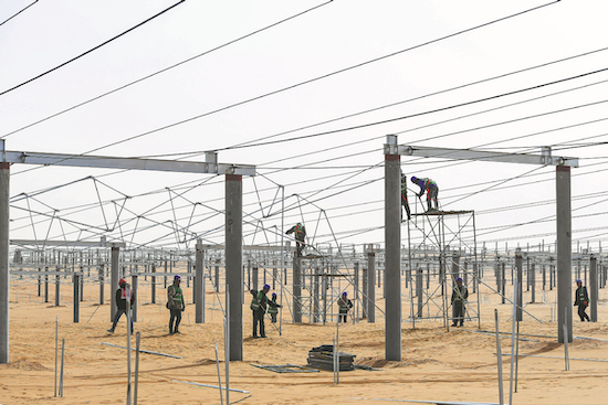 Des ouvriers mettent en place la structure d'une installation à énergie solaire dans le désert de Kubuqi situé dans la région autonome de Mongolie intérieure. (Photo/Xinhua)