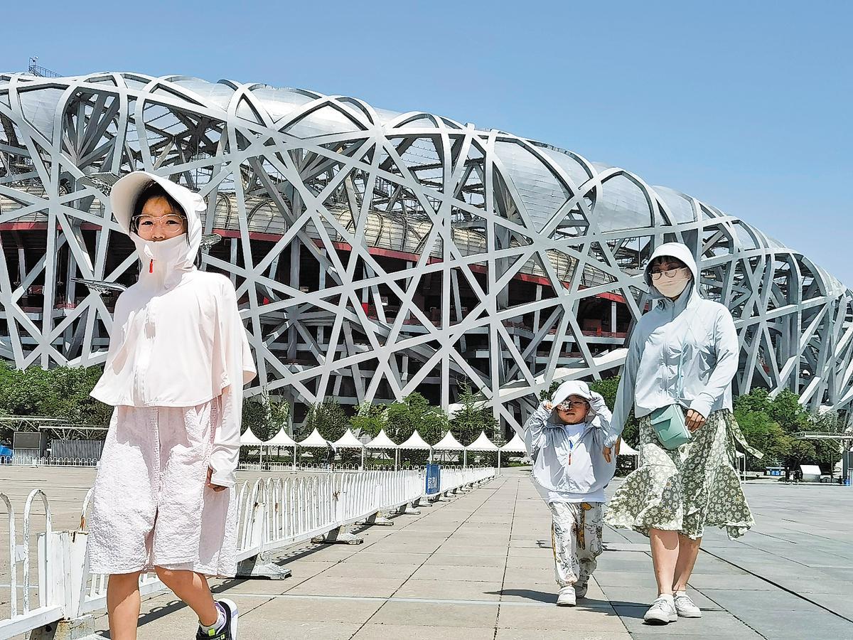 Des gens portent des vêtements de protection contre le soleil à l'extérieur du stade national de Beijing alors que la température maximale dans la capitale chinoise a atteint 40° C le 5 juillet. (Wang Jing / China Daily)