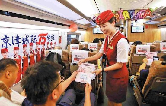 Un membre du personnel distribue des brochures commémoratives aux passagers à l'occasion du 15e anniversaire de la ligne de chemin de fer à grande vitesse qui relie Beijing à Tianjin. (Tong Yu/China News Service)