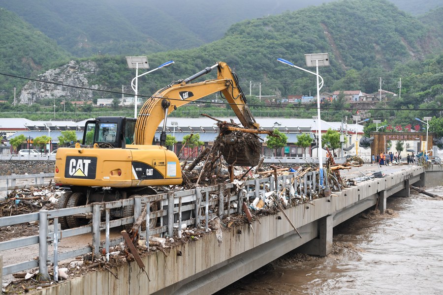 Une pelleteuse enlève les débris et les détritus accumulés sur un pont du village de Shuiyuzui, dans l