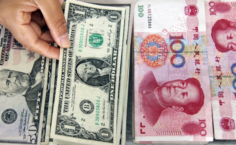 Photo d'archives d'un caissier prenant un billet d'un dollar parmi des billets de banque en dollar et en Renminbi (RMB) dans une banque à Linyi, dans la province chinoise du Shandong (est). (Photo : Zhang Chunlei)