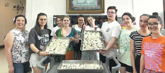 Vlad Savin (4e à partir de la droite) prépare des raviolis avec d'autres étudiants roumains le 17 juillet lors du camp d'été 2023 de l'Institut Confucius de l'Université Jianzhu de Shenyang-Université de Transylvanie de Brasov, en Roumanie. (China Daily)