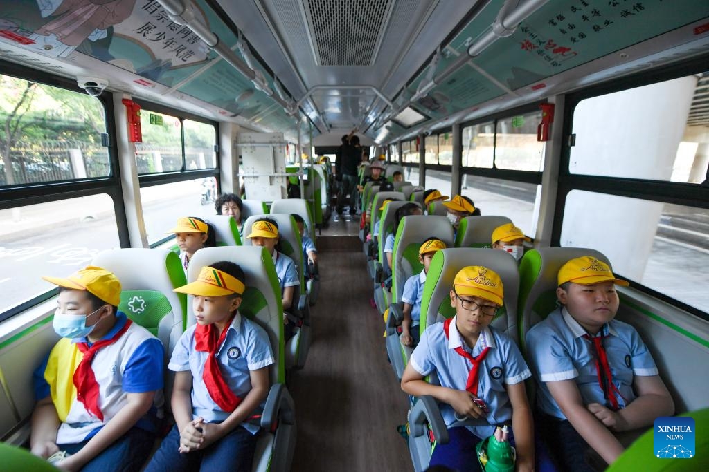 Des élèves d'une école primaire du district de Fengtai à Beijing descendent d'un bus scolaire conçu pour leur école. (Ju Huanzong / Xinhua)