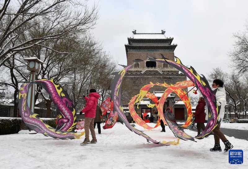 Des gens font danser des dragons de soie devant la Tour de la Cloche de Beijing. (Luo Xiaoguang / Xinhua)