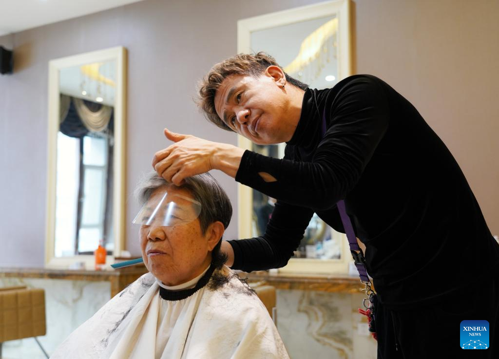 An Jong-euk, un coiffeur originaire de la République de Corée, coupe gratuitement les cheveux d'une vieille femme à Urumqi, capitale de la région autonome ouïgoure du Xinjiang (nord-ouest de la Chine), le 8 janvier 2024. (Aman / Xinhua)