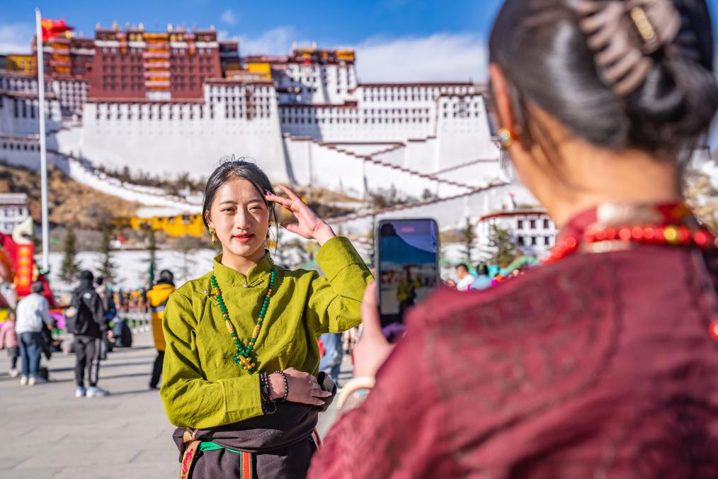 Une touriste pose pour des photos devant le Palais du Potala à Lhassa, dans la région autonome du Xizang (sud-ouest de la Chine), le 11 février 2024. (Photo : Sun Fei)