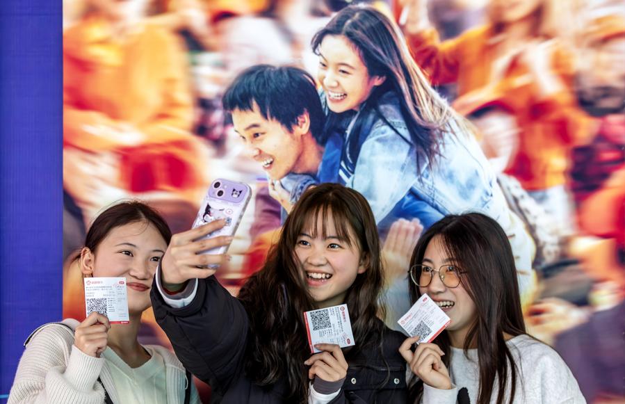 Des spectateurs prennent des selfies devant une affiche de film dans un cinéma de la ville de Qianxi, dans la province du Guizhou (sud-ouest de la Chine), le 18 février 2024. (Photo : Fan Hui)