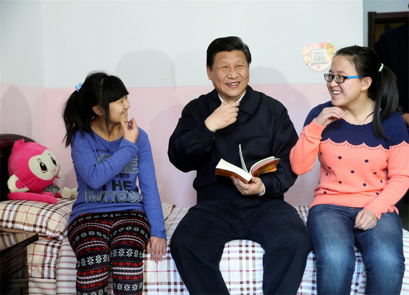 Xi Jinping encourage Wang Yani, jeune fille sourde-muette (à gauche) et sa camarade Yan Zhijing à étudier dur et à réussir leurs études dans le dortoir de l'Institut de protection de l'enfance de Hohhot, capitale de la région autonome de Mongolie intérieure (nord de la Chine), le 28 janvier 2014. (Photo / Lan Hongguang)
