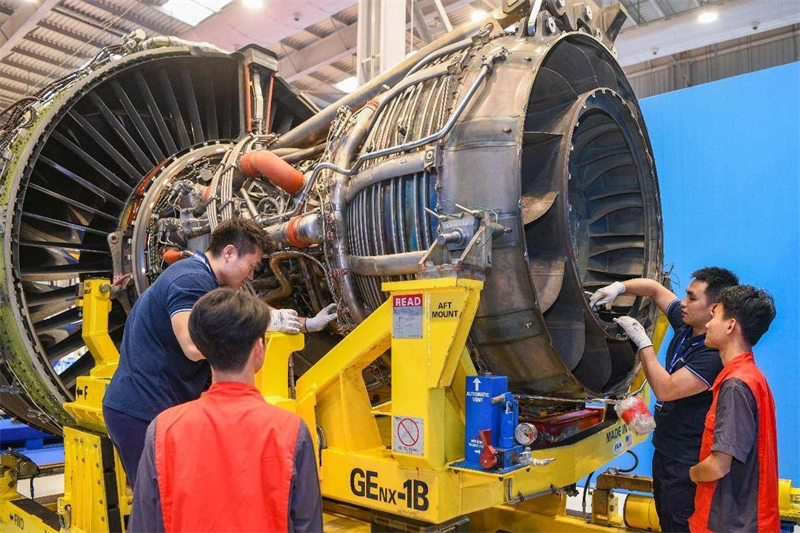 Du personnel inspecte les moteurs à livrer dans un atelier de réparation situé dans la zone sous douane intégrée de l'aéroport de Haikou, capitale de la province de Hainan (sud de la Chine). (Su Bikun / Pic.people.com.cn)