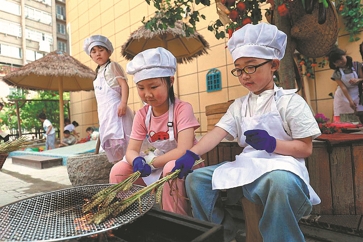 Des enfants rôtissent des épis de blé à l'école maternelle Xuhai Road à Xuzhou, dans la province du Jiangsu, le 23 mai. (Zhao Jiulong / Xinhua)