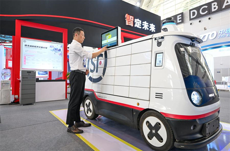 Un exposant utilise un véhicule de livraison autonome sans pilote présenté à l'Exposition mondiale de l'intelligence 2024, à Tianjin, dans le nord de la Chine, le 20 juin 2024. (Photo : Sun Fanyue)