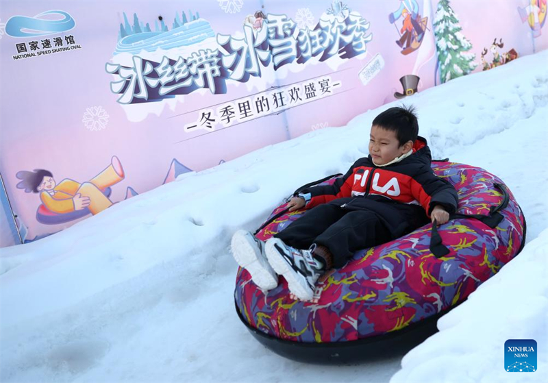 Les gens s'amusent avec de la glace et de la neige sur l'Anneau de patinage de vitesse de Beijing