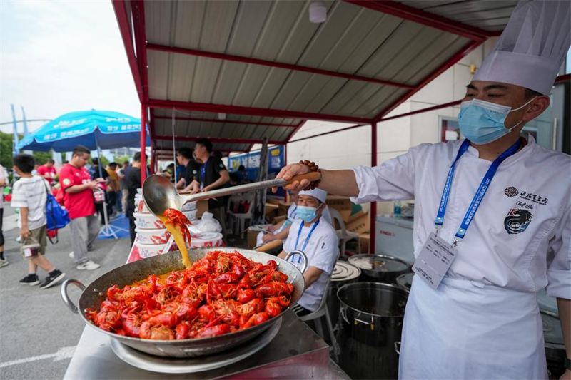 Un cuisinier prépare des écrevisses durant une foire lors d'un match de football entre l'équipe de Huai'an et celle de Nanjing, à Huai'an, ville de la province chinoise du Jiangsu (est), le 14 juin 2025. (Photo : Li Bo)