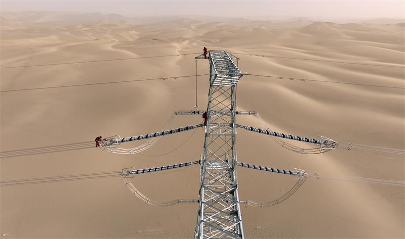 Xinjiang : des ouvriers électriciens corrigent les défauts du réseau avant sa mise en service dans le désert à Qiemo