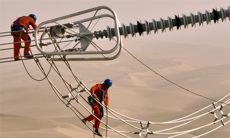 Xinjiang : des ouvriers électriciens corrigent les défauts du réseau avant sa mise en service dans le désert à Qiemo